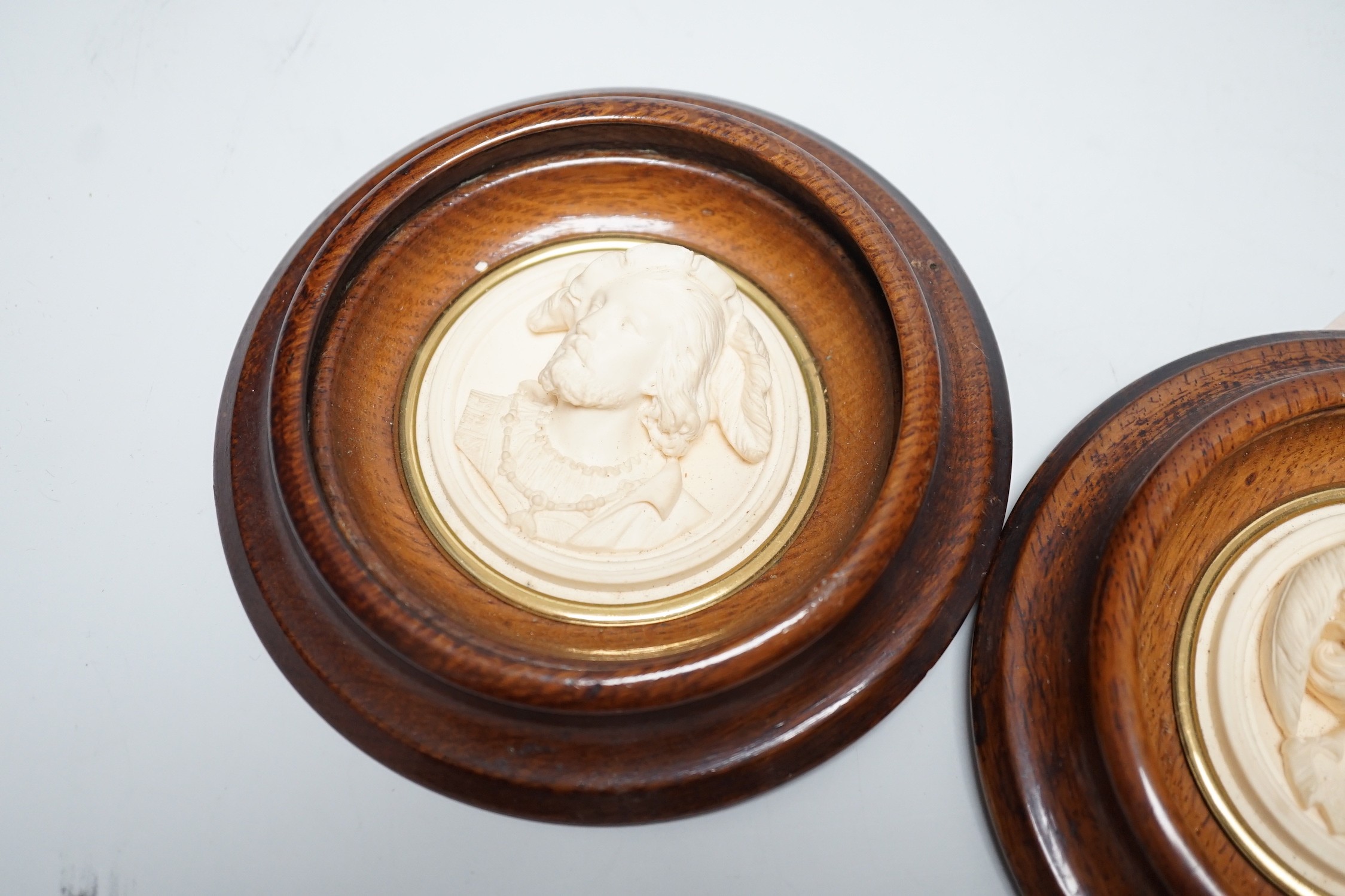 A pair of late 19th century carved and moulded composition portrait roundels, in oak frames